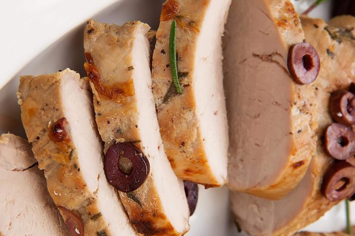 Closeup of delicious sliced roast pork tenderloin with olives.