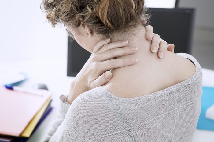 Woman holding her neck at the office.