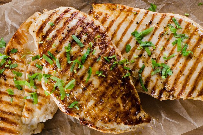 Grilled chicken breast on dark wooden background.