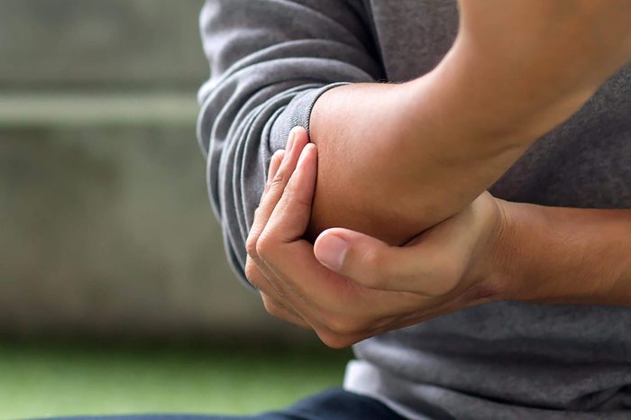 Man holding his elbow as if having joint pain.