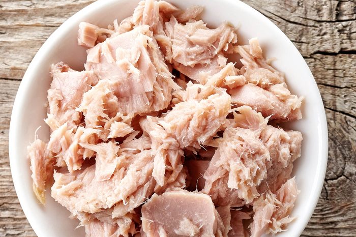 Bowl of canned tuna on wooden background.