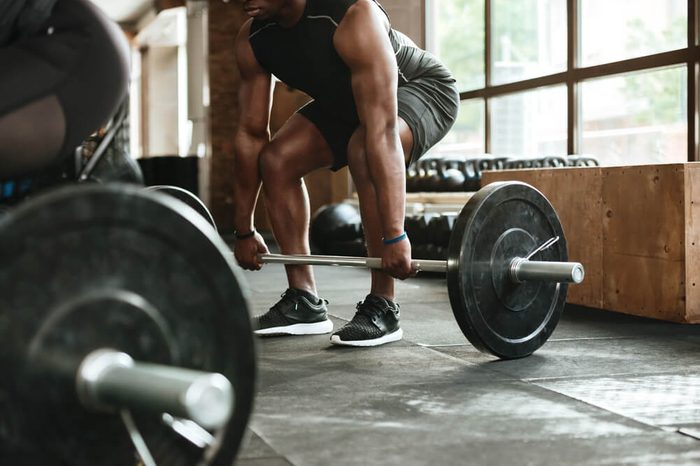 A person lifting a barbell at the gym.