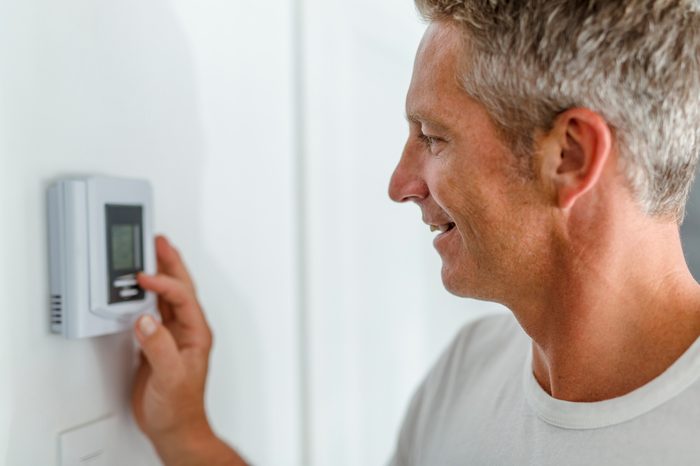 man adjusting the thermostat at home