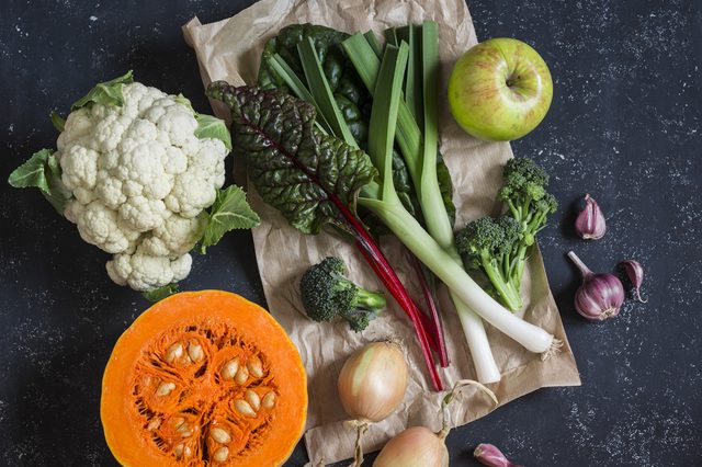 Homegrown harvest - pumpkin, cauliflower, chard, leeks, broccoli, onion, garlic, apple. Autumn vegetables. On a dark background, top view