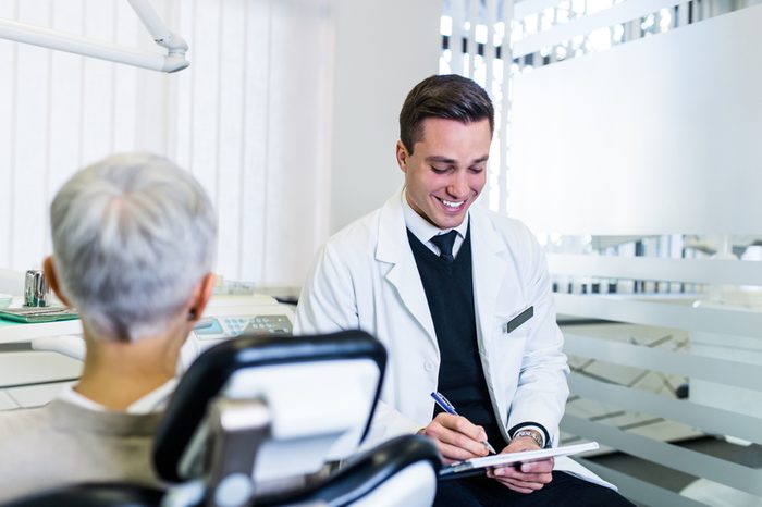 Handsome male dentist looking at dental x-ray together with his beautiful senior woman patient.