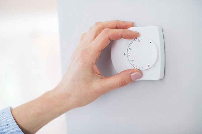 Female Hand On Central Heating Thermostat