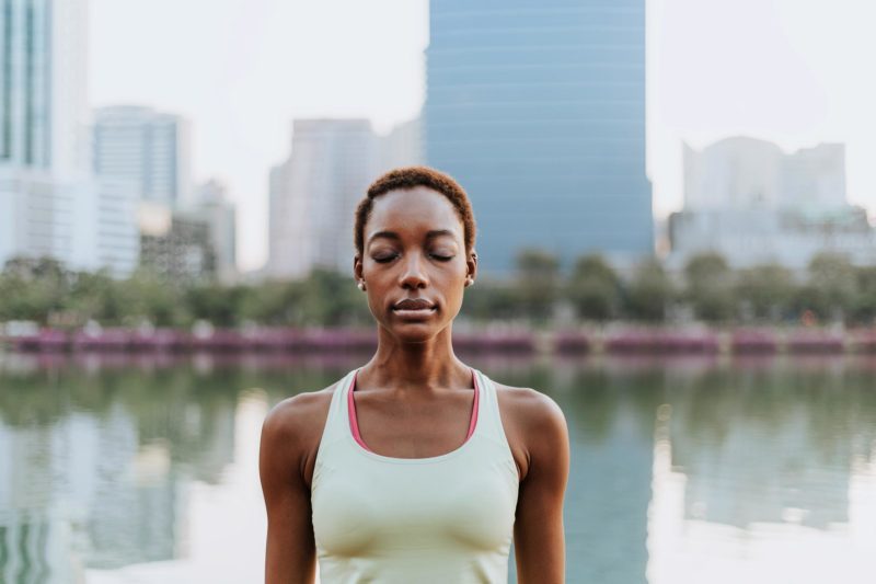 Black lady making a meditation at a park