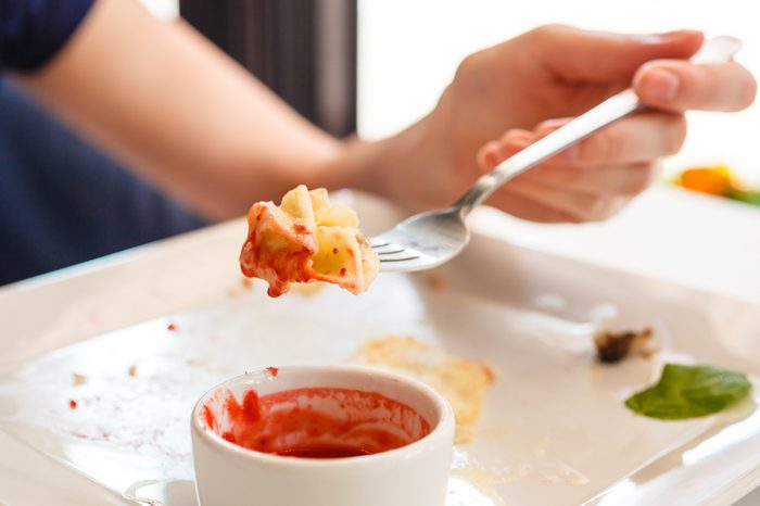 Woman at dinner table eating with the fork in her left hand