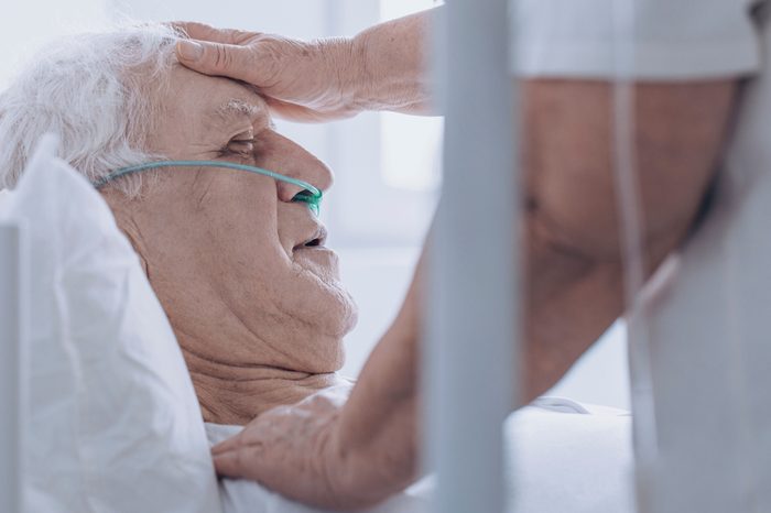 Close-up of a person taking care of sick senior man, touching his forehead