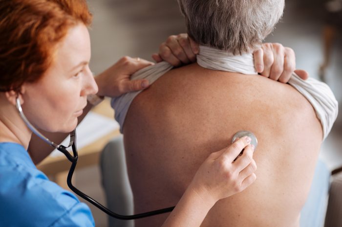 Clinician listening to patient's lungs with a stethoscope.