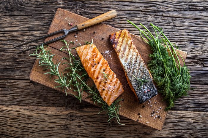 Grilled salmon fillets with salt pepper and herb decoration.