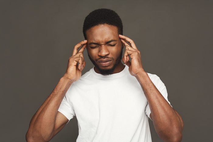 Pensive black man thinking about something, holding fingers on temples.