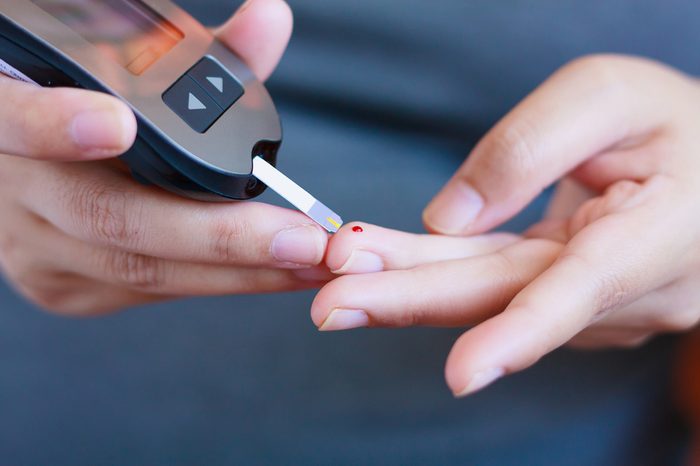 woman testing her blood sugar with a glucometer on ring finger