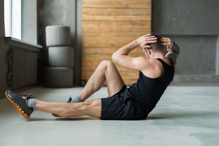 Young man workout in fitness club. Closeup portrait of caucasian guy making exercise, sit-ups and cross crunches for abs muscles, training indoors