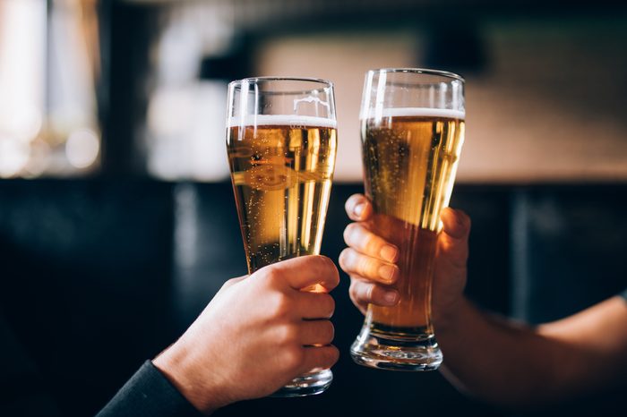 Cheers. Close-up of two men in shirts toasting with beer at the bar counter