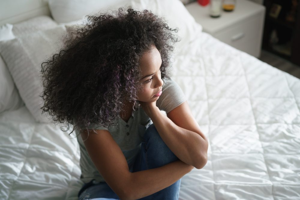 woman sitting on bed, looking sad