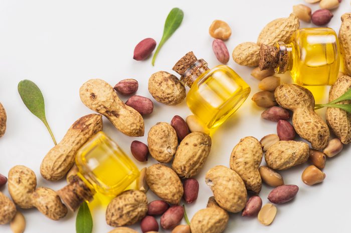 Bottles of oil surrounded by shelled and unshelled peanuts