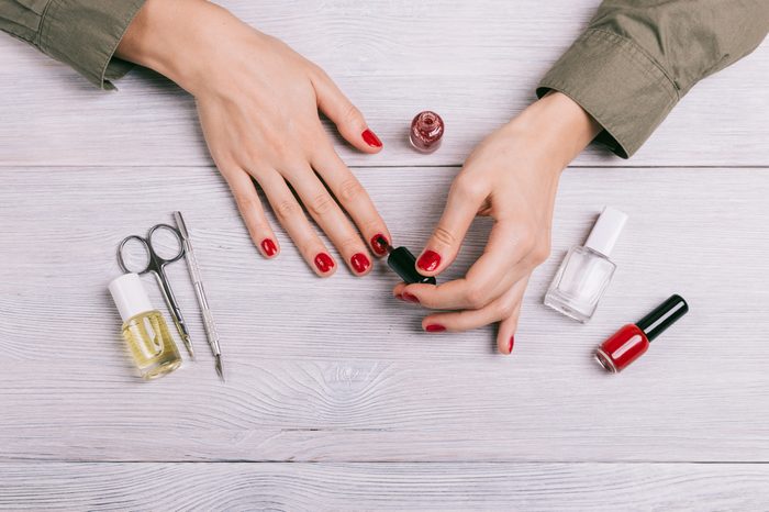 Top view of a woman doing a manicure and paint nails with red lacquer