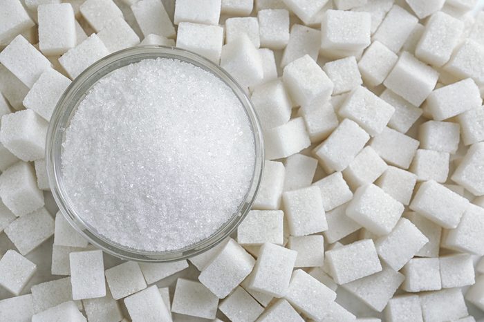 Granulated sugar in jar on sugar cubes