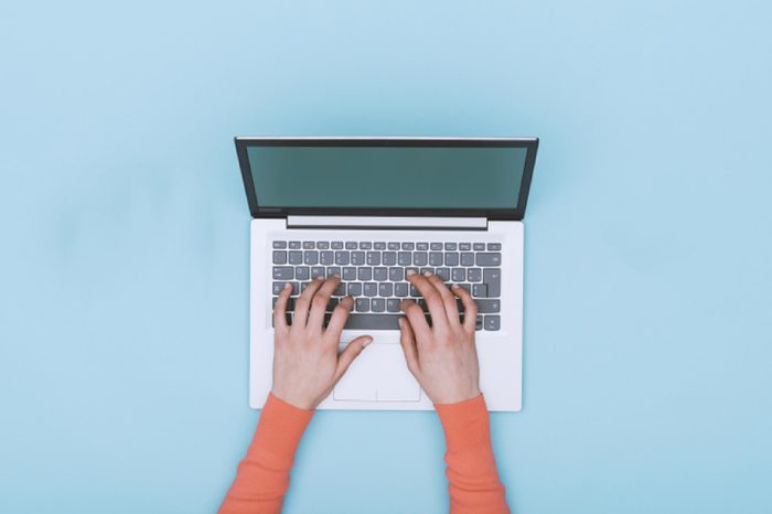 Hands typing on a laptop keyboard.