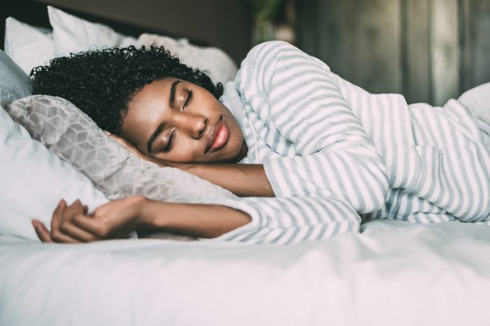 close up of a pretty black woman with curly hair sleeping in bed closed eyes