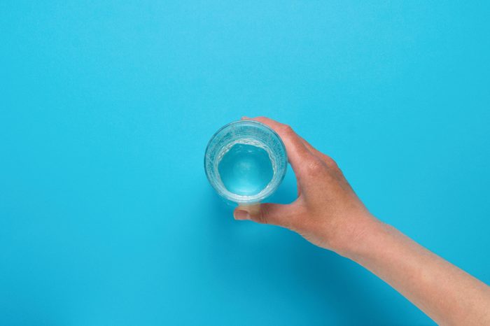 Female hand taking a glass of water.