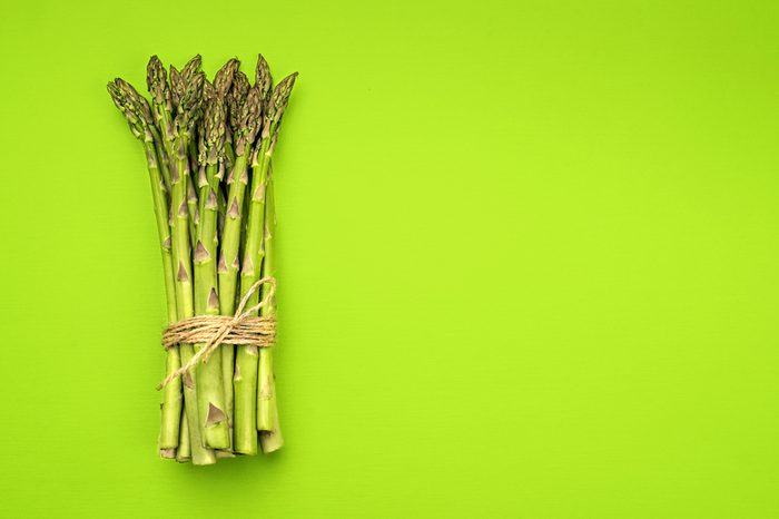 A bunch of fresh green asparagus on green background.