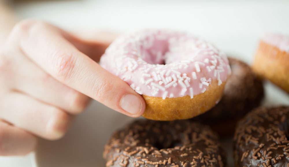 emale hand holding glazed doughnut