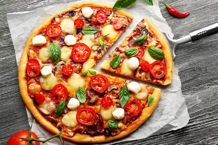 Fresh pizza with tomatoes, cheese and mushrooms on wooden table closeup