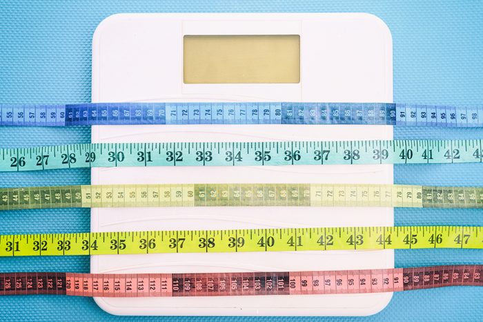 Bathroom scale and measure tapes on a blue background.