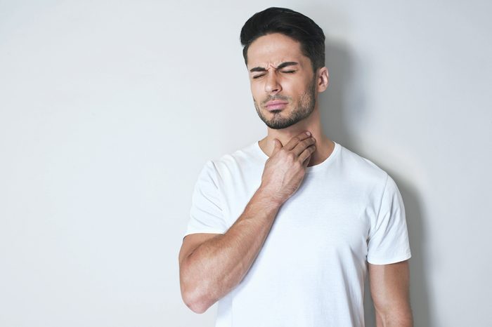 Man with sore throat touching his neck