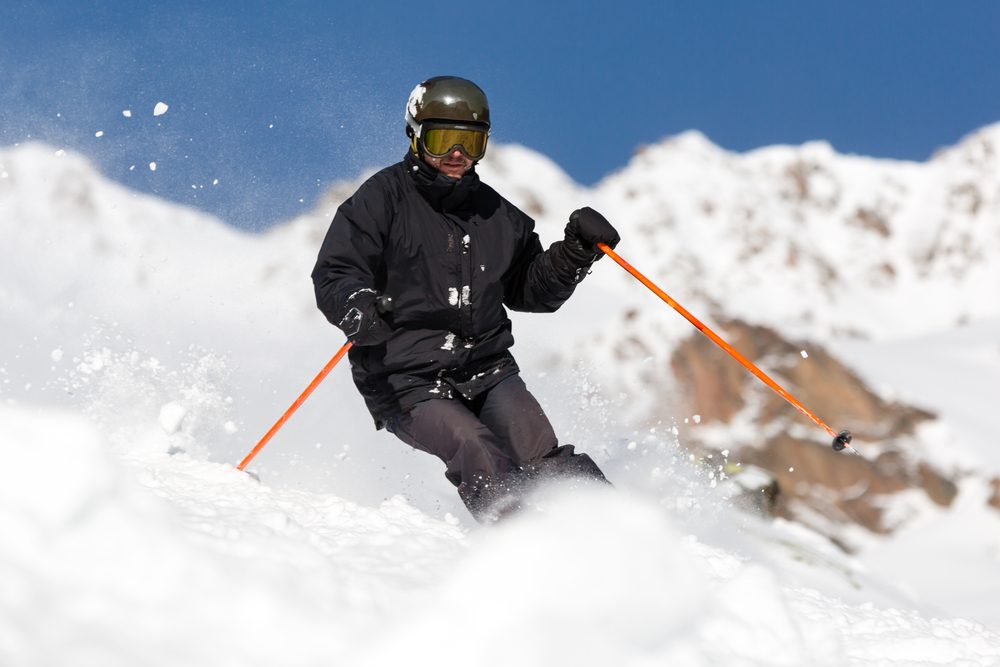 Male skier skiing in fresh snow on ski slope on a sunny winter day at the ski resort 