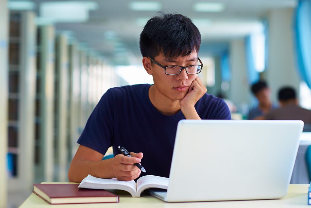 college student studying in the library with laptop