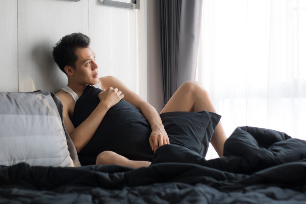 man in bed, hugging a pillow