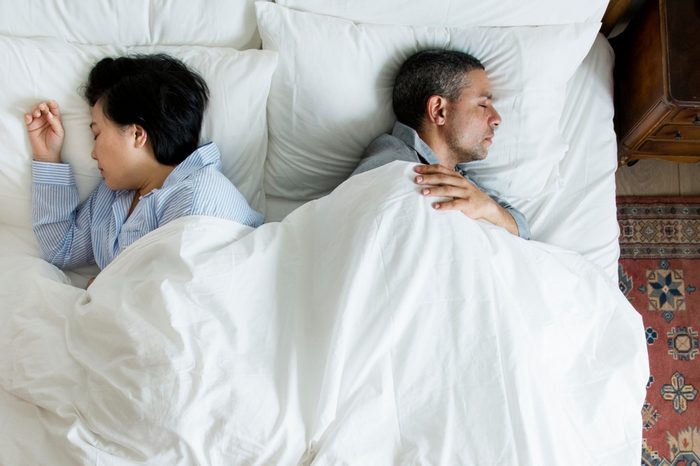 Interracial couple sleeping back to back on the bed