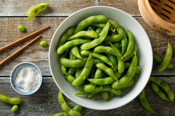 Fresh steamed edamame sprinkled with sea salt on a rustic tabletop.