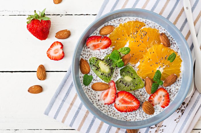 Detox and healthy superfoods breakfast in bowl. Vegan almond milk chia seeds pudding with strawberries, orange and kiwi. Top view. Flat lay