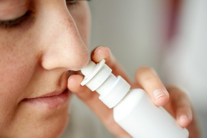 healthcare, flu, rhinitis, medicine and people concept - close up of sick woman using nasal spray