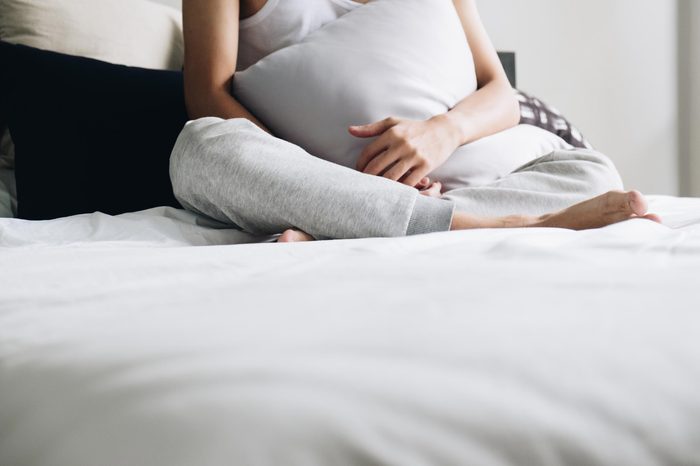 woman sitting on bed holding pillows