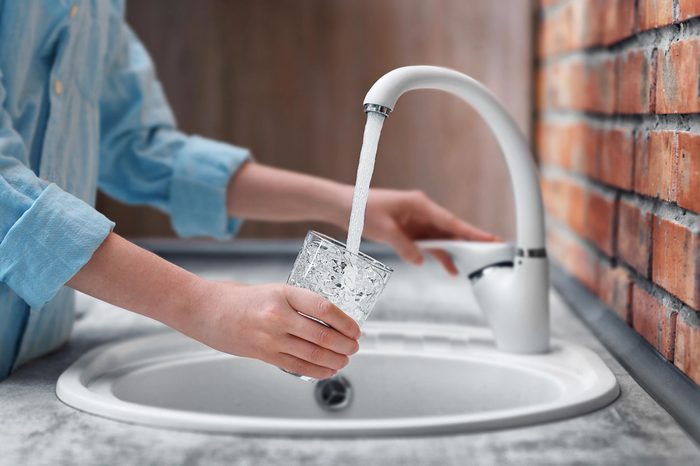 woman filling a glass of water a a sink