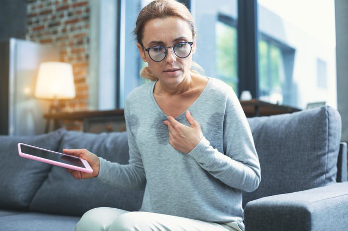 middle aged woman having hot flash sweating with tablet