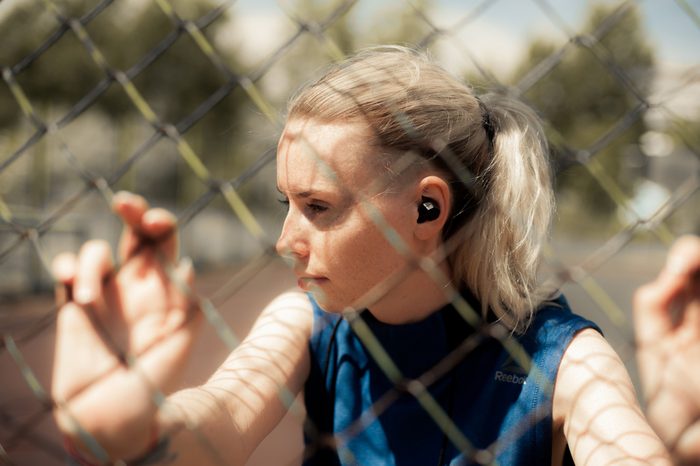 Fitness Woman Listening Music in Wireless Headphones, Doing Workout Exercises On Street. Beautiful Athletic Fit Girl Relaxing After Training. Sport style 