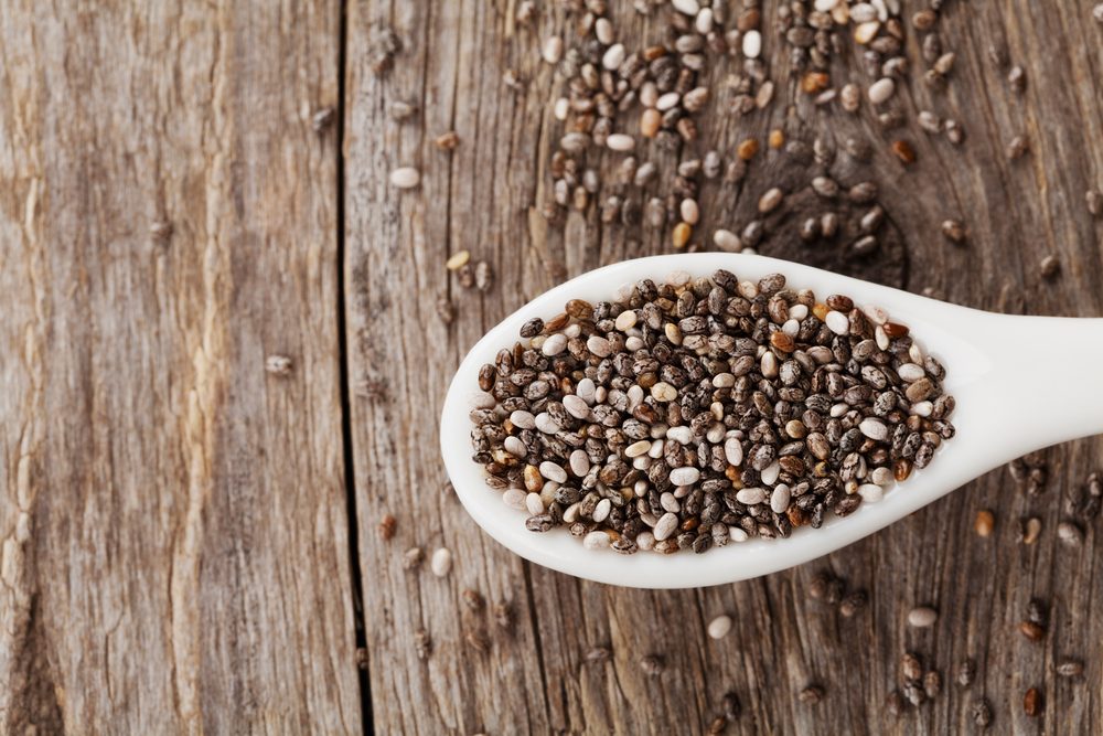 Chia seeds in white spoon on wooden table