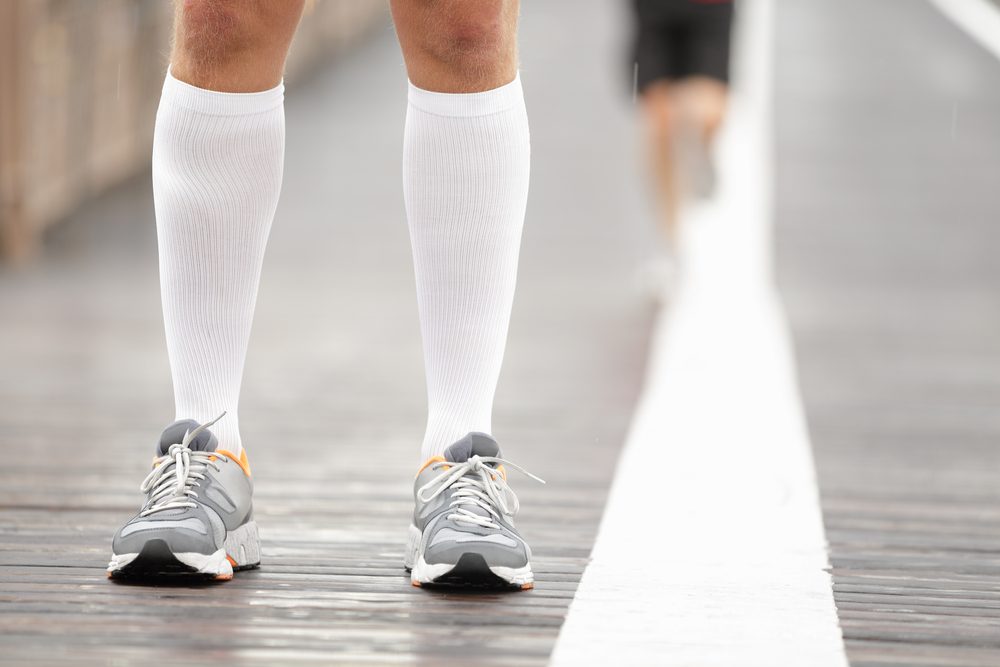 Running shoes closeup and compression socks on male runner. Closeup of runners feet on Brooklyn Bridge, New York City.