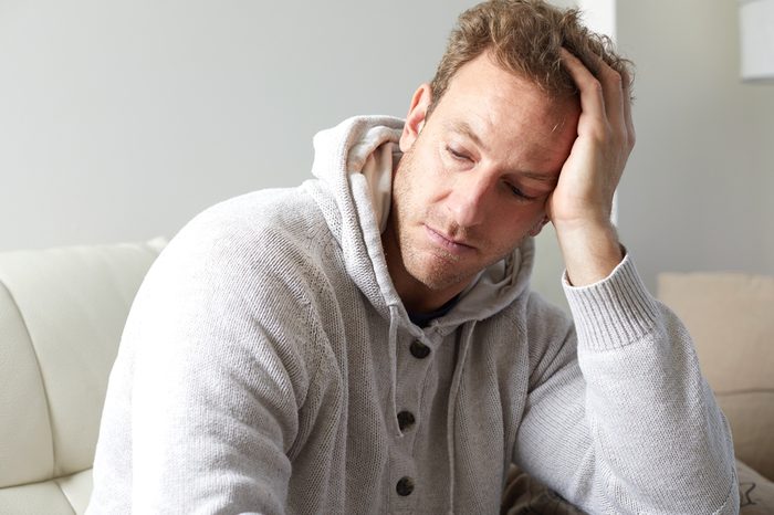 Man in a cardigan looking fatigued.