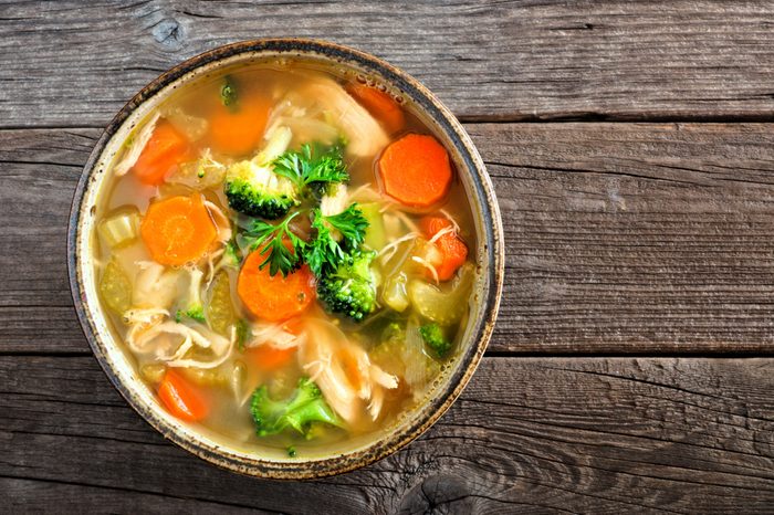 Homemade chicken vegetable soup, overhead, close up view on an old wood background