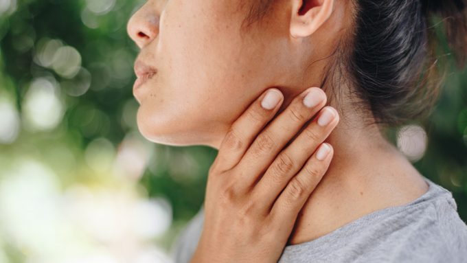 woman holding neck and throat