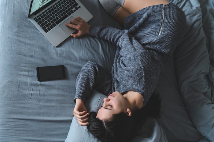 woman lying on a bed using a laptop 