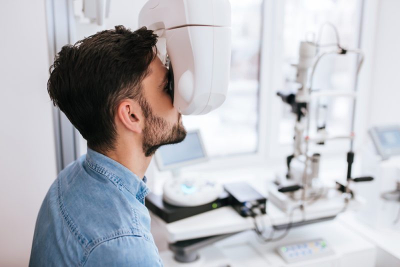 Handsome young man is checking the eye vision in modern ophthalmology clinic. Patient in ophthalmology clinic