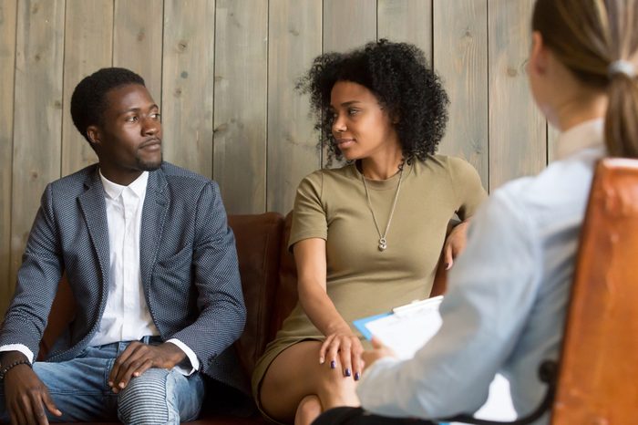 Reconciled black husband and wife looking at each other after successful psychological treatment from relationship counselor, African spouses make peace at therapy session, lovers ready to compromise